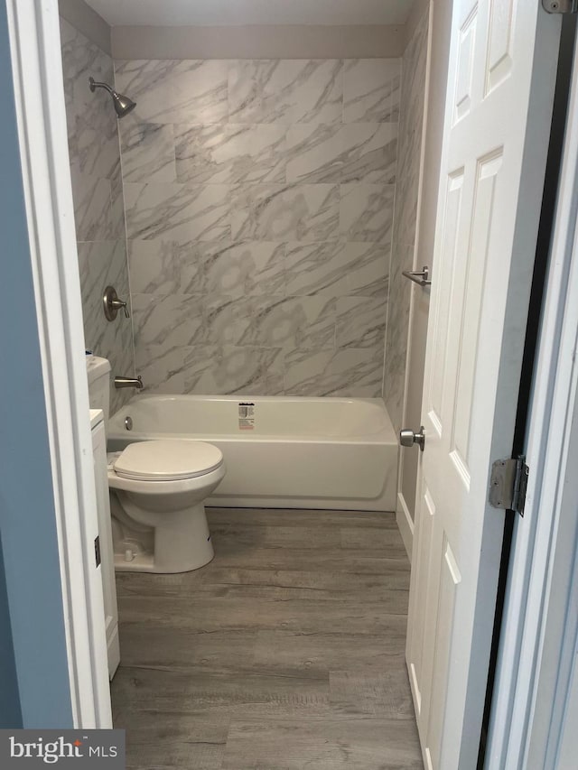 bathroom with tiled shower / bath, wood-type flooring, and toilet