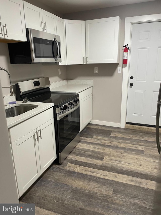 kitchen featuring white cabinetry, stainless steel appliances, and dark wood-type flooring