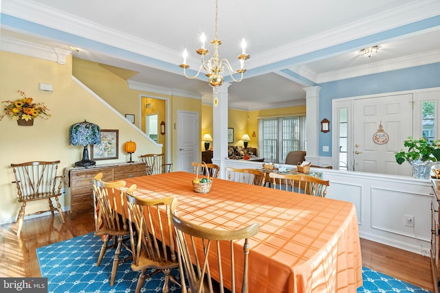 dining room featuring ornamental molding, a notable chandelier, ornate columns, and light wood-type flooring