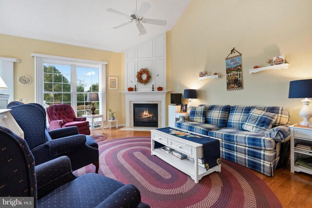 living room with hardwood / wood-style flooring, a large fireplace, ceiling fan, and vaulted ceiling