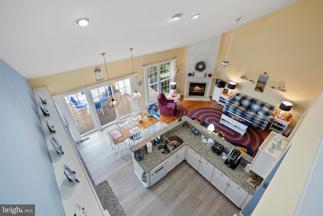 living room with light hardwood / wood-style floors, a large fireplace, and ceiling fan