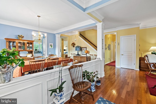 interior space featuring an inviting chandelier, ornamental molding, wood-type flooring, and decorative columns