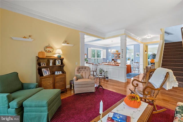 living room with crown molding, a chandelier, wood-type flooring, and ornate columns