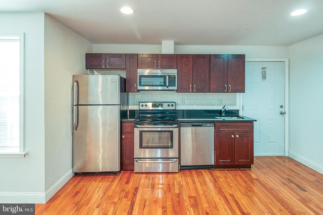 kitchen with light hardwood / wood-style floors, tasteful backsplash, appliances with stainless steel finishes, and sink