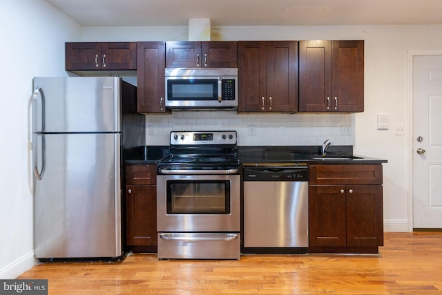 kitchen with sink, appliances with stainless steel finishes, light wood-type flooring, and tasteful backsplash