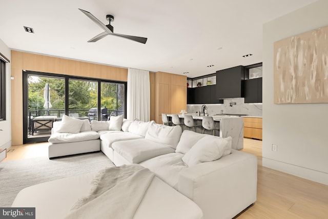 living room with light wood-type flooring, ceiling fan, and sink