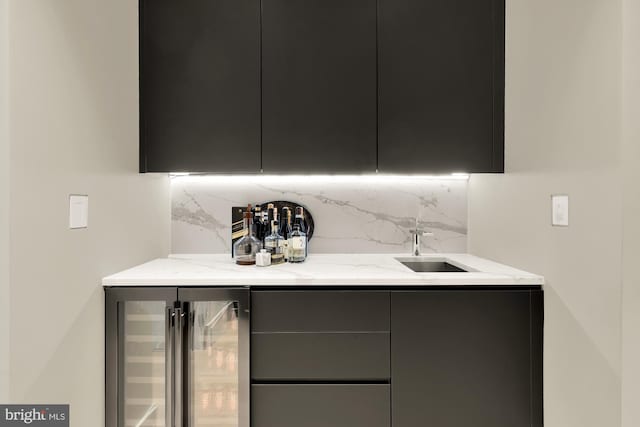 kitchen with sink, light stone counters, tasteful backsplash, and wine cooler