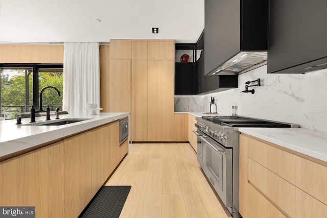 kitchen featuring sink, light hardwood / wood-style flooring, light brown cabinetry, backsplash, and high end stainless steel range