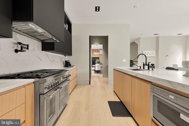 kitchen with light stone counters, appliances with stainless steel finishes, light hardwood / wood-style flooring, and light brown cabinets