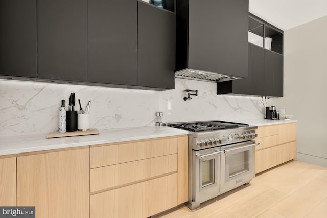 kitchen with range with two ovens, backsplash, and light brown cabinets