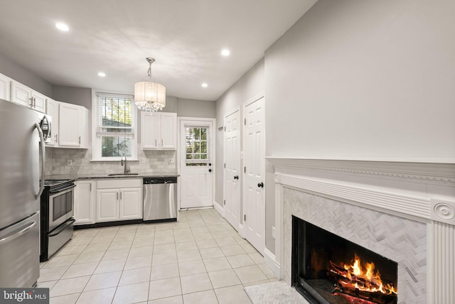 kitchen with white cabinetry, stainless steel appliances, sink, and a fireplace