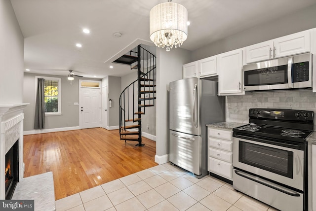 kitchen featuring decorative backsplash, white cabinets, hanging light fixtures, appliances with stainless steel finishes, and light hardwood / wood-style floors