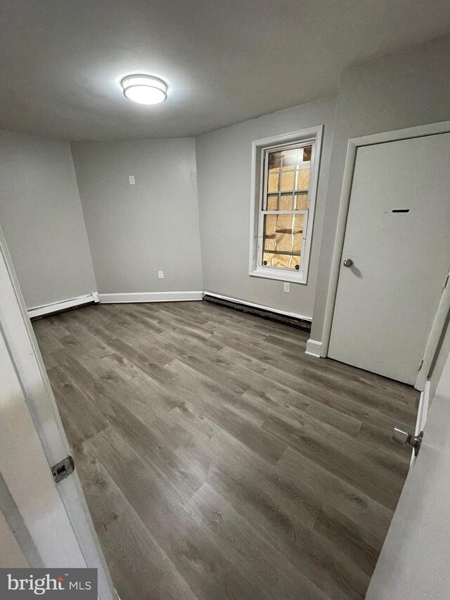 empty room featuring hardwood / wood-style flooring and a baseboard radiator