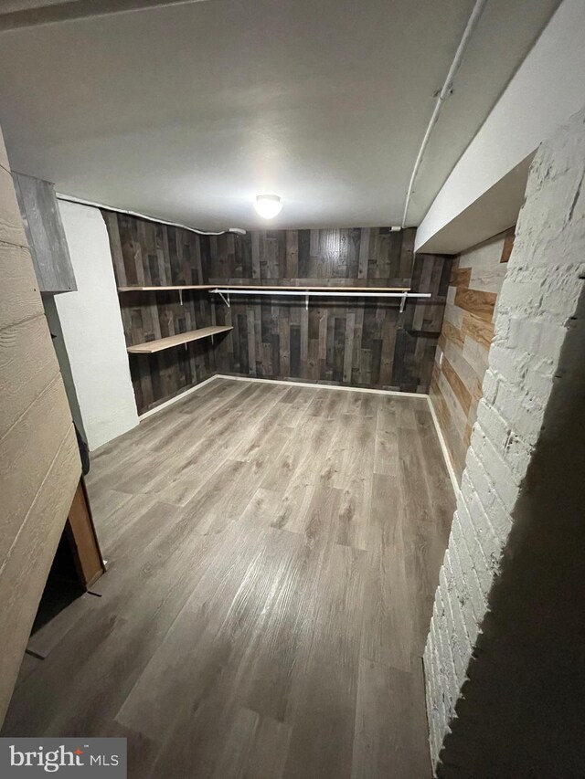 basement with light hardwood / wood-style flooring and wooden walls