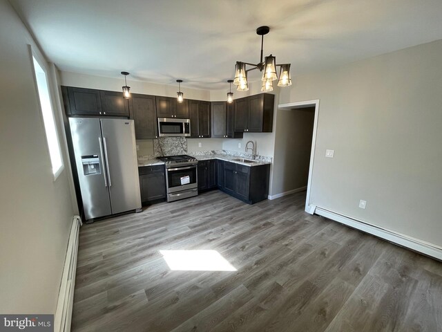 kitchen with sink, decorative light fixtures, stainless steel appliances, and light wood-type flooring