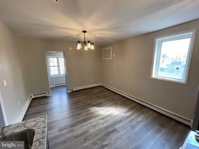 empty room with dark wood-type flooring, a baseboard heating unit, and an inviting chandelier