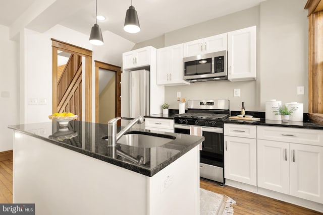 kitchen with appliances with stainless steel finishes, light hardwood / wood-style flooring, white cabinetry, and sink