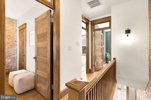 hallway featuring wood-type flooring and brick wall