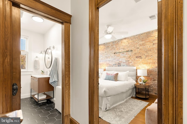 bedroom with ceiling fan, dark hardwood / wood-style flooring, brick wall, and radiator heating unit