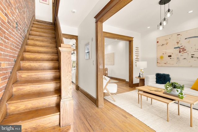 staircase featuring hardwood / wood-style floors and brick wall