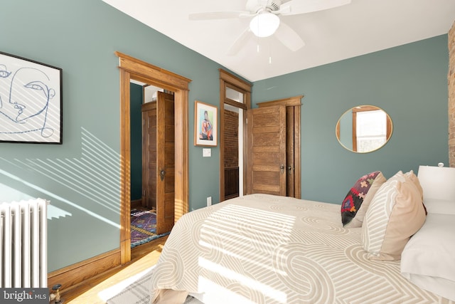 bedroom with ceiling fan, wood-type flooring, and radiator