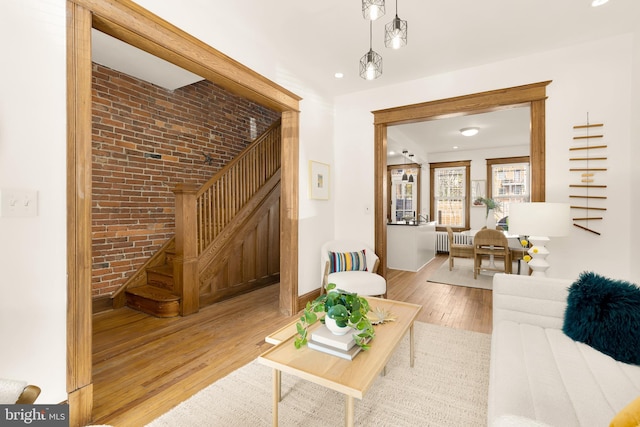 living room featuring brick wall and light hardwood / wood-style flooring