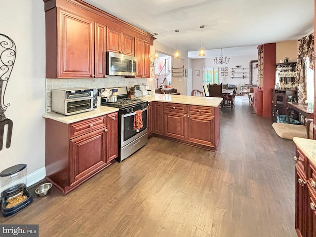 kitchen featuring appliances with stainless steel finishes, kitchen peninsula, plenty of natural light, decorative light fixtures, and dark wood-type flooring