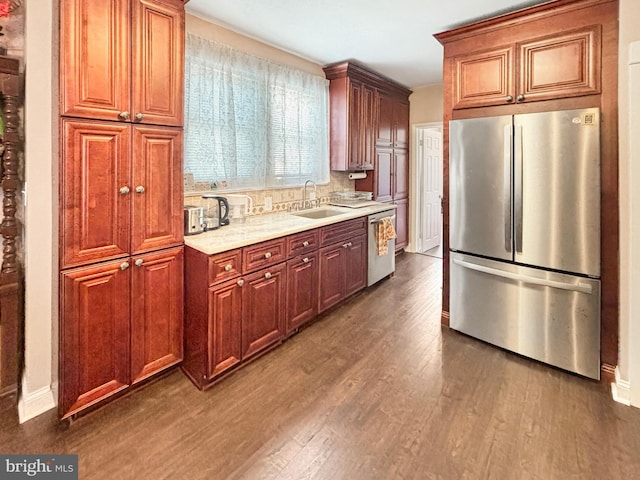 kitchen featuring appliances with stainless steel finishes, dark hardwood / wood-style floors, light stone countertops, and sink