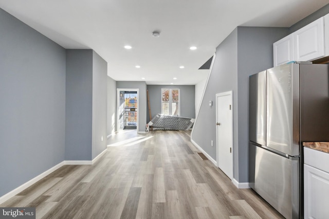 kitchen featuring stainless steel fridge, white cabinets, and light hardwood / wood-style floors