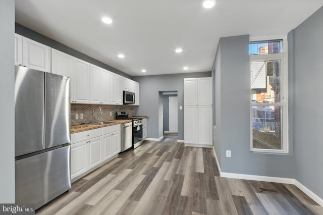 kitchen featuring appliances with stainless steel finishes, light hardwood / wood-style flooring, white cabinets, and sink