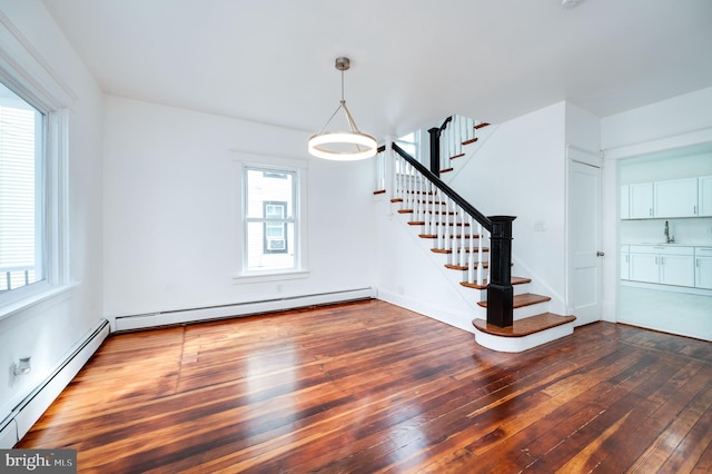 interior space with a baseboard heating unit, sink, and dark hardwood / wood-style flooring