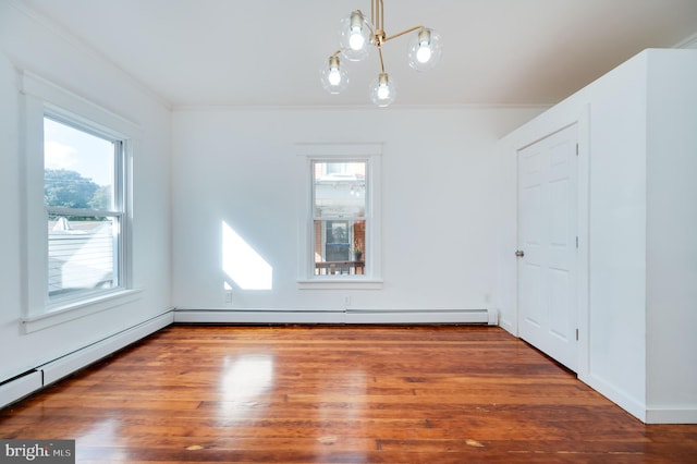 empty room featuring dark wood-type flooring, a baseboard heating unit, crown molding, and an inviting chandelier