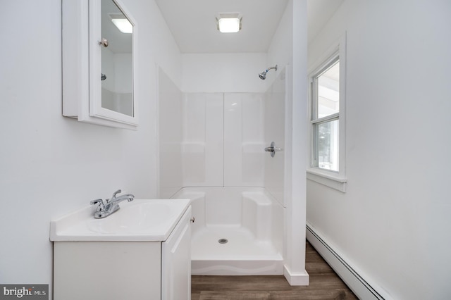 bathroom with vanity, wood-type flooring, walk in shower, and baseboard heating