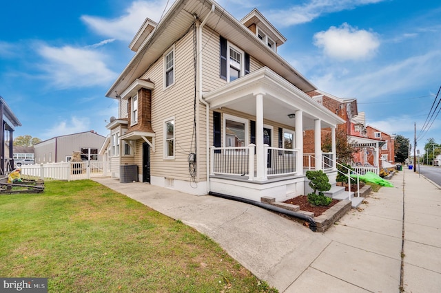 view of front of property with central AC, a front yard, and a porch