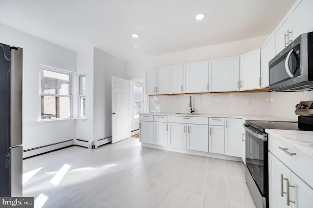 kitchen with stainless steel appliances, backsplash, sink, white cabinetry, and light stone counters