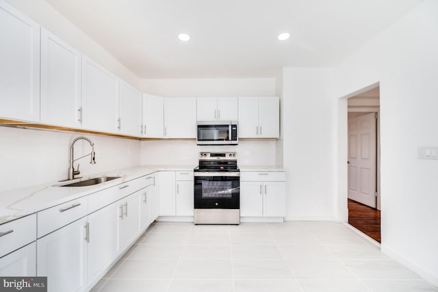 kitchen featuring white cabinets, tasteful backsplash, light stone counters, appliances with stainless steel finishes, and sink