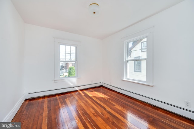 empty room with a baseboard heating unit, wood-type flooring, and a wealth of natural light