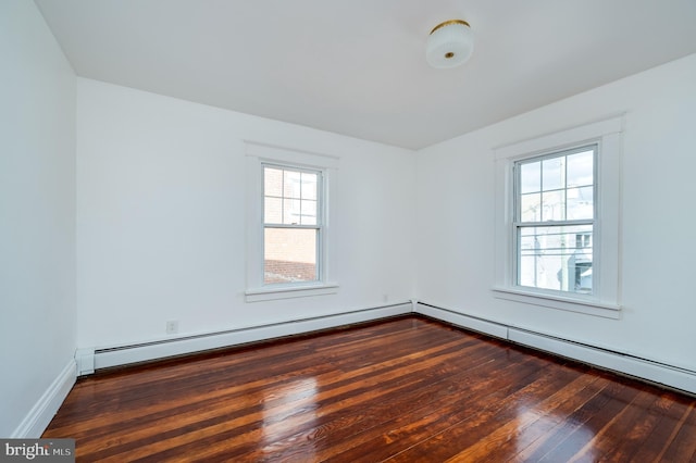 spare room with baseboard heating and dark hardwood / wood-style floors