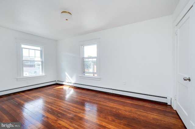 empty room with dark hardwood / wood-style flooring, baseboard heating, and plenty of natural light