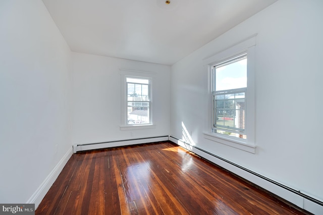 unfurnished room with a healthy amount of sunlight, baseboard heating, and dark wood-type flooring