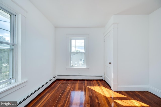 empty room with dark hardwood / wood-style floors and baseboard heating