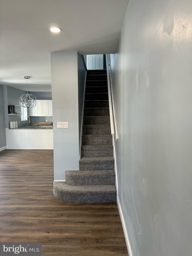 stairway with hardwood / wood-style floors, a chandelier, and sink