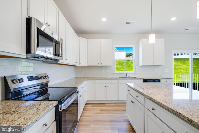 kitchen featuring stainless steel appliances, hanging light fixtures, a wealth of natural light, and white cabinets