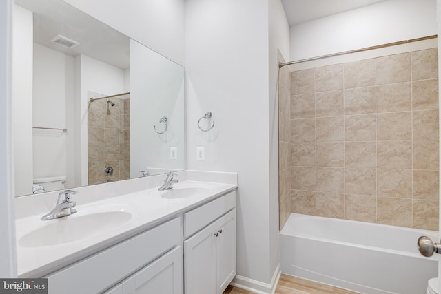 full bathroom featuring toilet, tiled shower / bath, hardwood / wood-style floors, and vanity