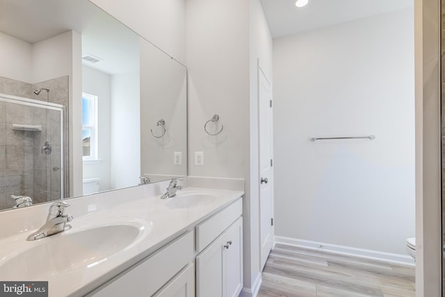 bathroom featuring vanity, toilet, a shower with shower door, and hardwood / wood-style floors