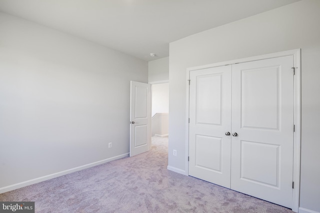 unfurnished bedroom with light carpet and a closet