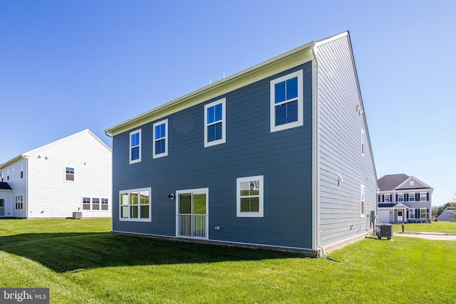 rear view of house featuring central AC and a lawn