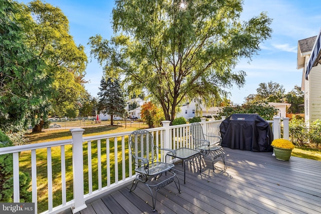 wooden terrace featuring area for grilling and a lawn