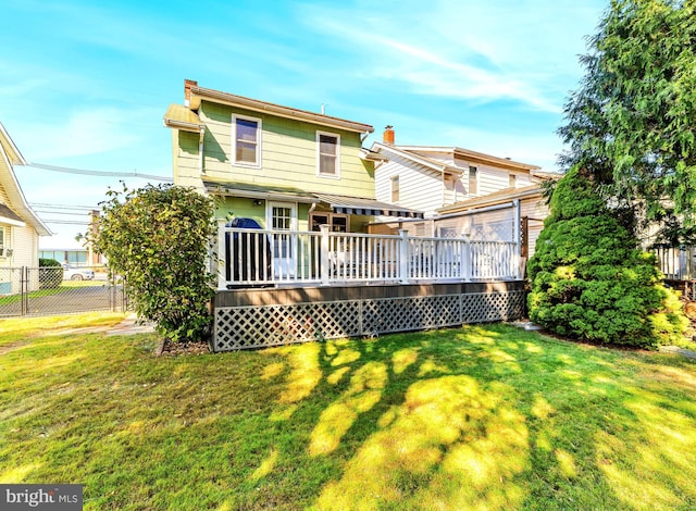 back of property with a deck and a lawn