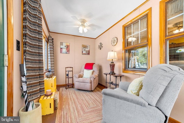 living area with ornamental molding, wood-type flooring, and ceiling fan